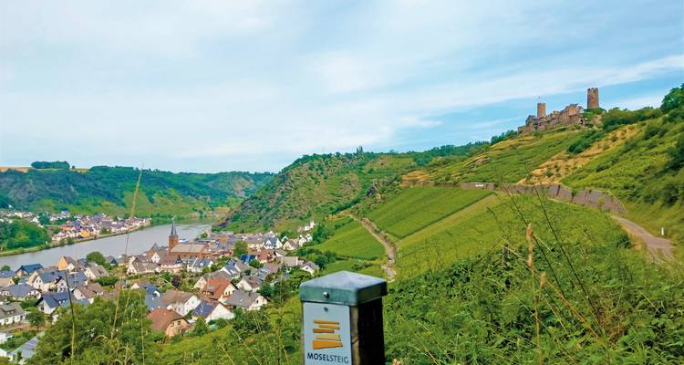 Vue panoramique depuis une colline sur une vallée fluviale et une ville avec un panneau indicateur au premier plan.