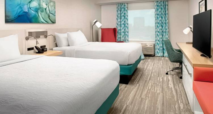 Chambre d'hôtel double queen avec mobilier moderne et équipements.