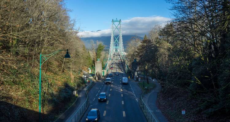 Vue du pont à travers les arbres avec circulation visible, menant aux montagnes.