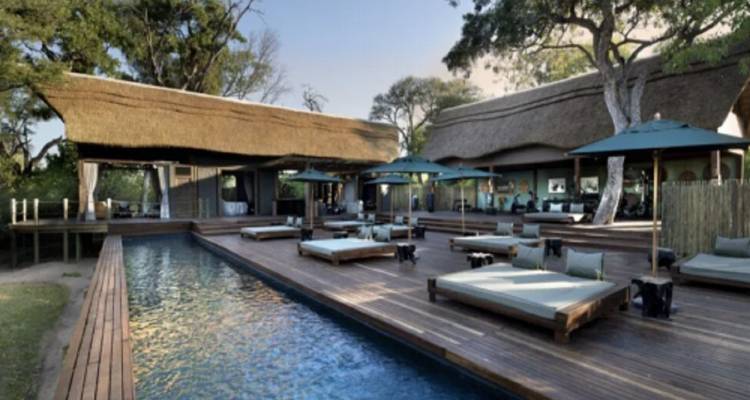 Lodge with a swimming pool and lounge area amidst greenery.