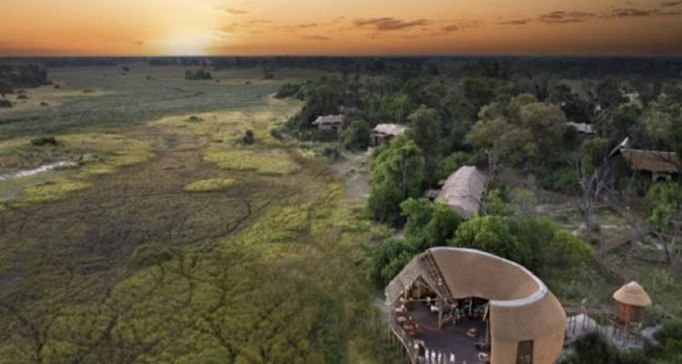 Aerial view of a safari lodge with the vast landscape at sunset.