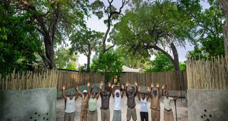 Group of people raising hands, standing in a natural setting.