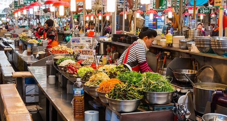 Marché animé avec des étals de nourriture et des lampes suspendues colorées.