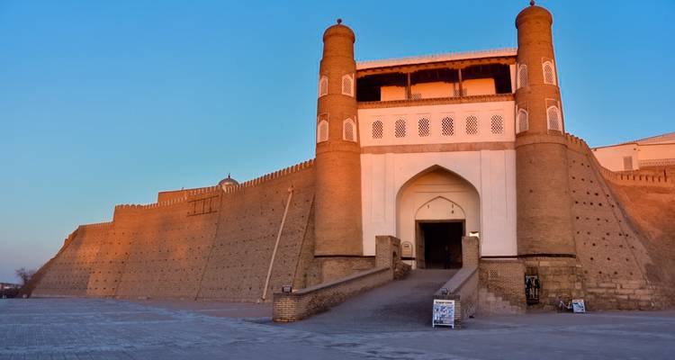 Une grande forteresse historique avec une entrée majestueuse au coucher du soleil.