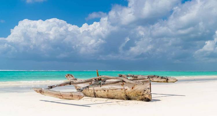Traditionelles Holzboot auf einem weißen Sandstrand.