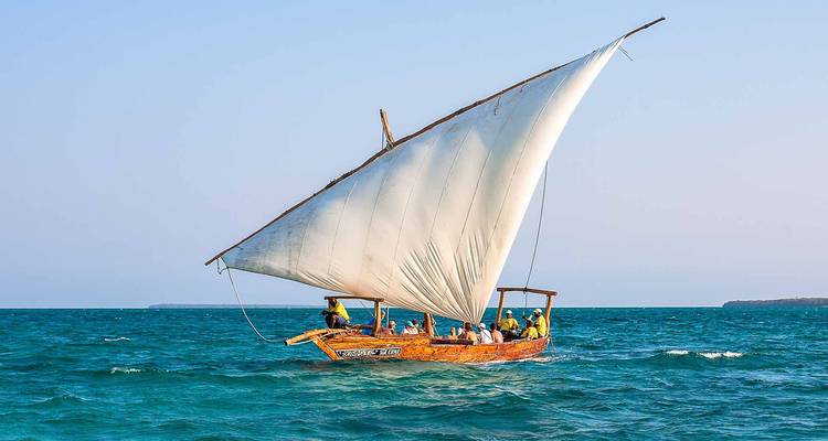Traditionelles Segelboot navigiert auf blauem Wasser mit Menschen an Bord.