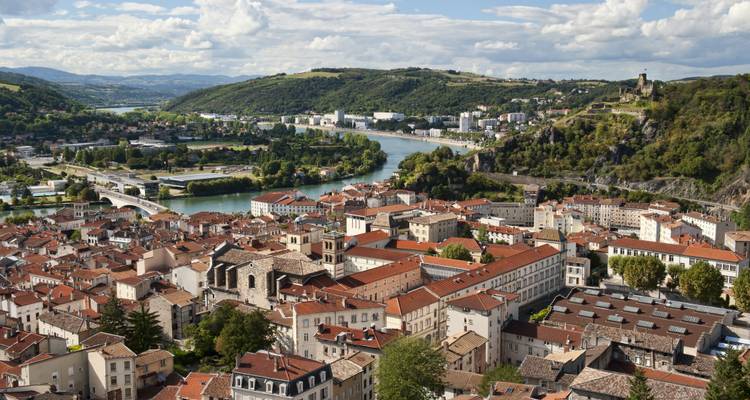 Winding river through a historic town surrounded by hills.