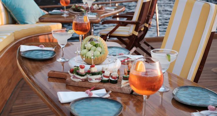 Variété d'apéritifs et de boissons sur une table à bord d'un bateau.