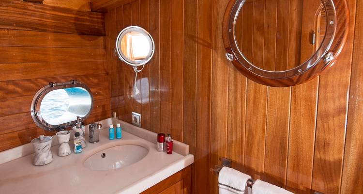 Baño de madera con lavabo y ojo de buey en un barco.
