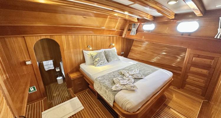 Camarote con una cama y ojos de buey en un barco de madera.