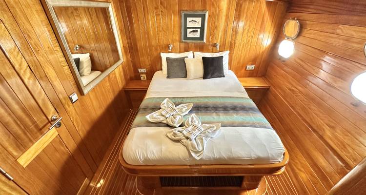 Cabaña de madera con una cama y espejo en un barco.