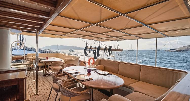 Buiteneetruimte op een zeilboot met zeezicht en andere boten in de verte.