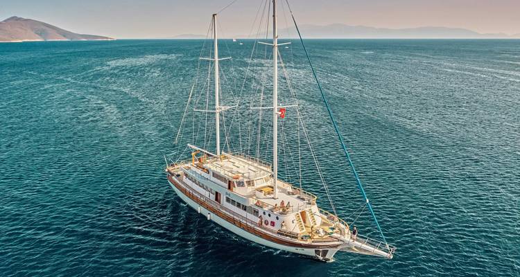 Luchtfoto van een grote zeilboot in de oceaan met mensen aan dek.