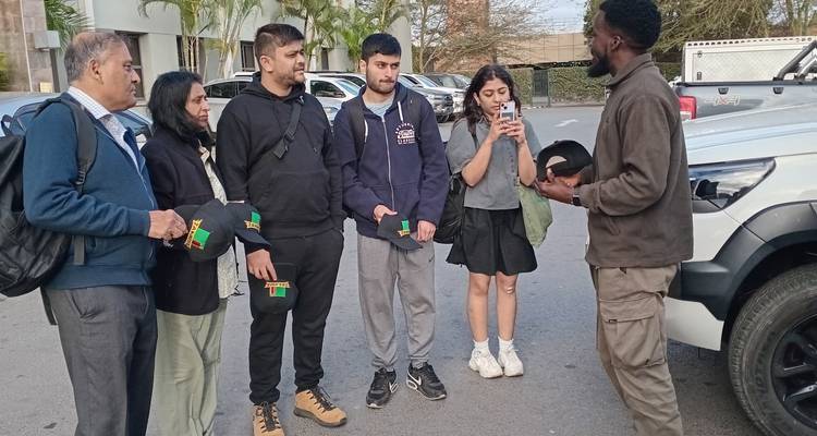 Guide touristique expliquant à un groupe de touristes à côté d'un véhicule.