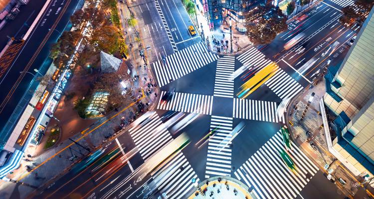Vue aérienne d'un passage piéton urbain animé avec des voitures en mouvement et des lumières.