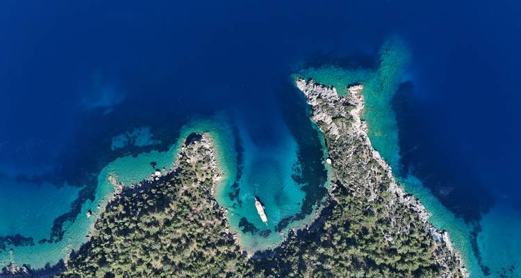 Vue aérienne d'une côte rocheuse avec une mer d'un bleu profond.
