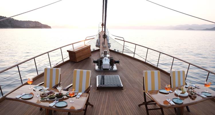 Configuration de dîner élégante sur un yacht avec vue sur l'océan au coucher du soleil.