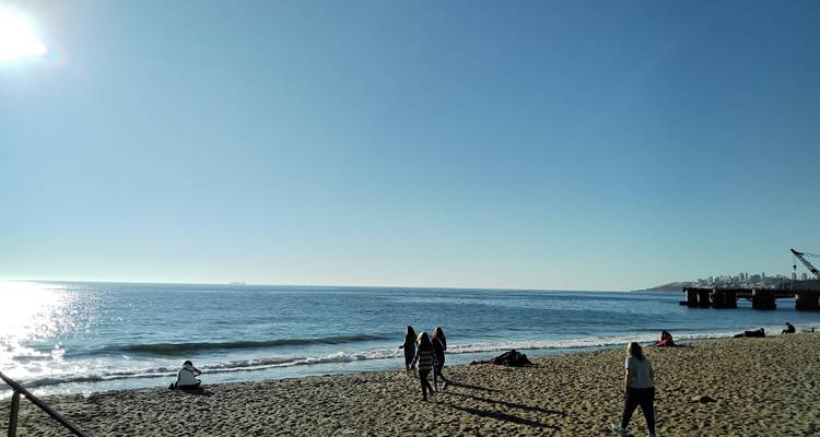 Des gens qui marchent sur une plage de sable au bord de la mer.