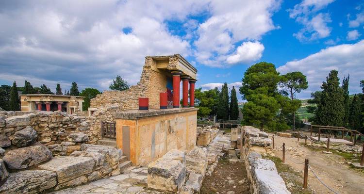 Ruines d'un ancien palais minoen avec des colonnes rouges distinctives.