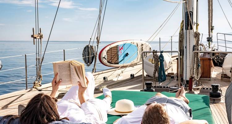 People relaxing on deck of a sailboat.