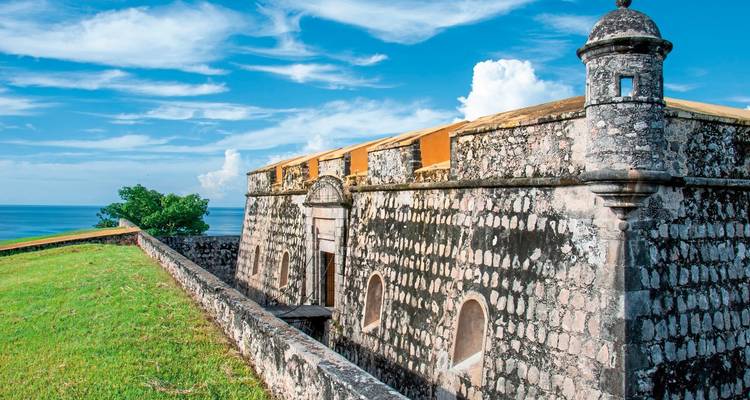 Historical fort overlooking the sea under a bright blue sky.