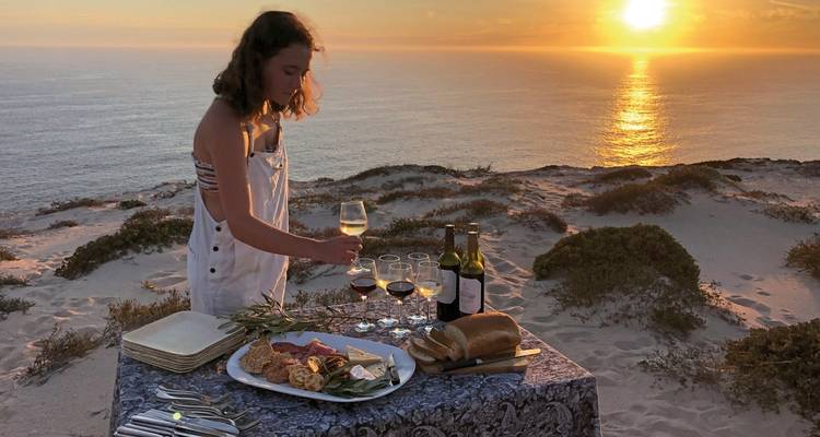 Femme préparant un dîner au coucher du soleil au bord de l'océan.