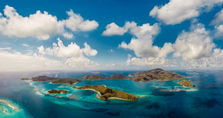 Aerial view of islands surrounded by blue ocean and white clouds.