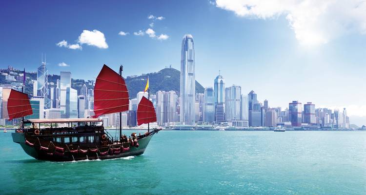 Bateau-jonque traditionnel dans le port de Hong Kong avec l'horizon de la ville en arrière-plan.