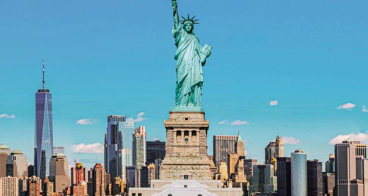 Freiheitsstatue mit der Skyline von New York City im Hintergrund.
