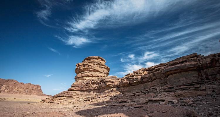 Desert landscape with rock formations and blue sky.