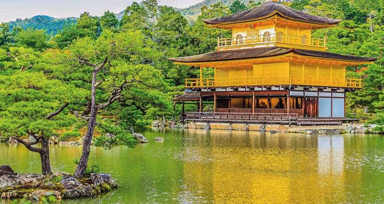 A golden temple reflected in a pond surrounded by lush greenery.