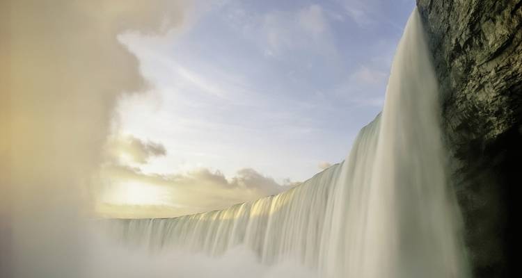 Seitenansicht der Niagarafälle mit Nebel, der vom Fuß aufsteigt.