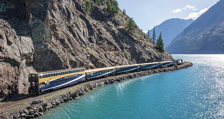 Train traveling alongside a scenic mountainous lake view in British Columbia.