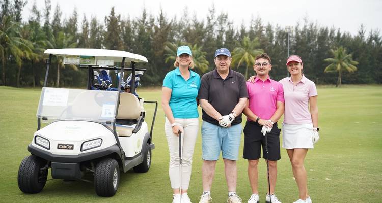 Groep poseert naast een golfkar op de baan.