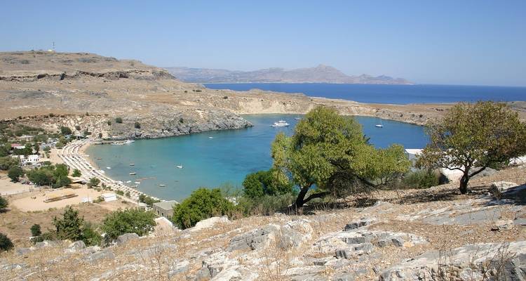 Baie côtière entourée de collines rocheuses et d'eaux claires.