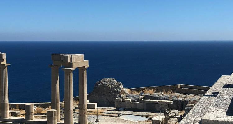 Ruines anciennes surplombant une mer d'un bleu profond.