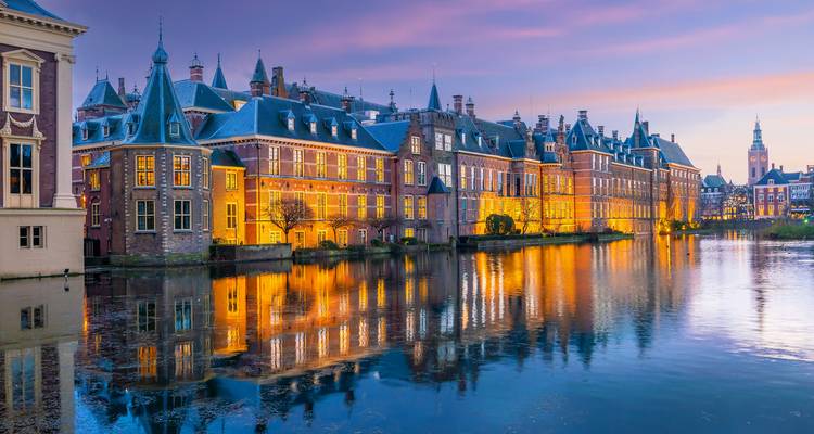 Bâtiments historiques reflétés dans un canal au coucher du soleil.