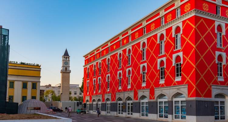 Bâtiment rouge coloré avec une tour d'horloge sous un ciel bleu.