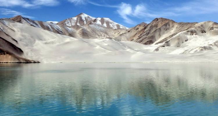 A calm lake reflecting snowy mountain peaks in a serene setting.