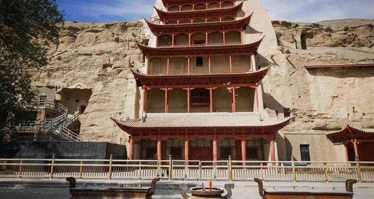 Traditional Chinese pagoda built into a cliffside with a clear sky background.