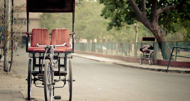 An empty rickshaw parked on a street with a subdued color palette.