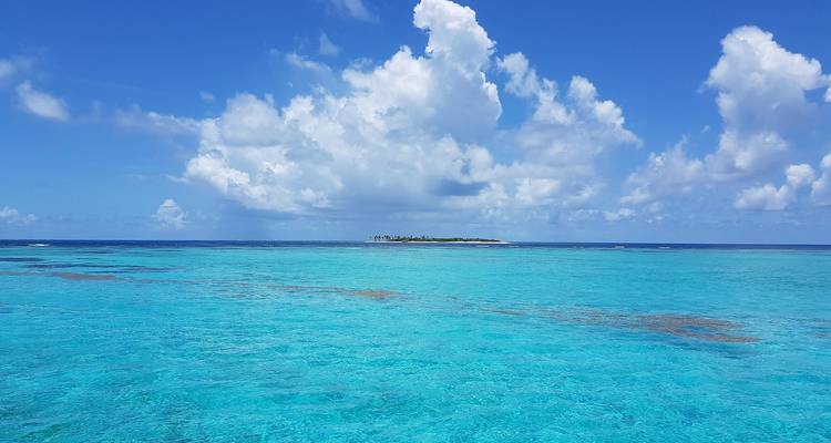 Vast view of blue ocean and distant island under a clear sky.