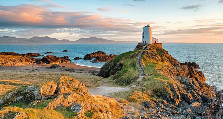 Phare sur une colline entouré d'un littoral rocheux.