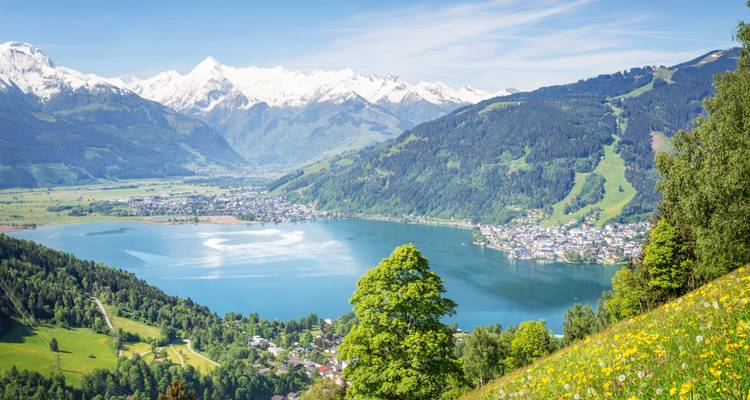 Ein malerischer See mit einer Stadt und Bergen in der Ferne.