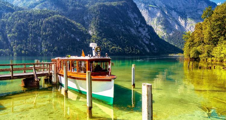 Ein Boot liegt an einem klaren See vor, umgeben von üppigen Bergen.
