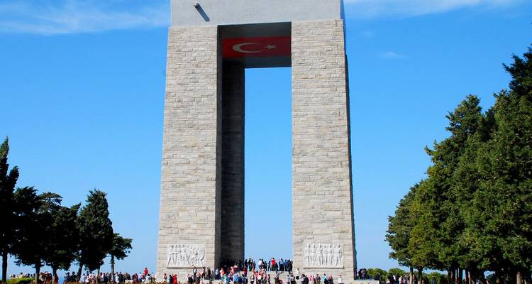 Las multitudes se reúnen bajo el imponente Memorial de los Mártires de Çanakkale que se eleva contra el cielo azul.