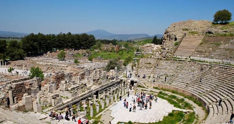 Ruines d'un amphithéâtre antique avec des touristes qui explorent.