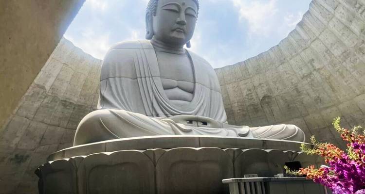 Large, serene Buddha statue in an outdoor circular structure.