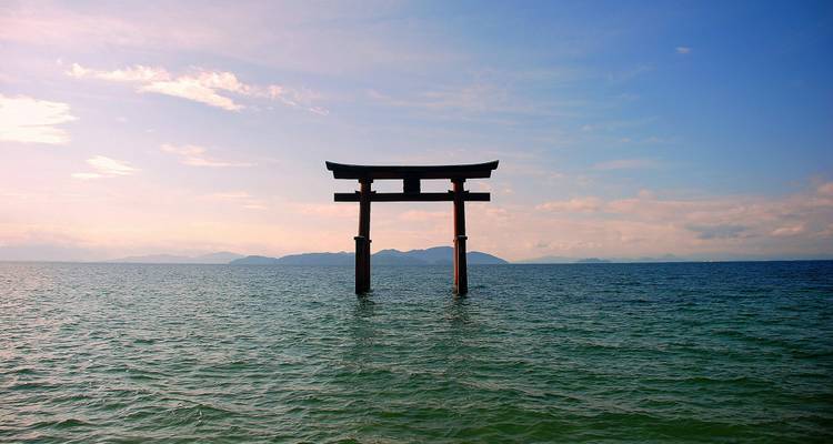 Portique torii se dressant dans l'eau avec un arrière-plan pittoresque.
