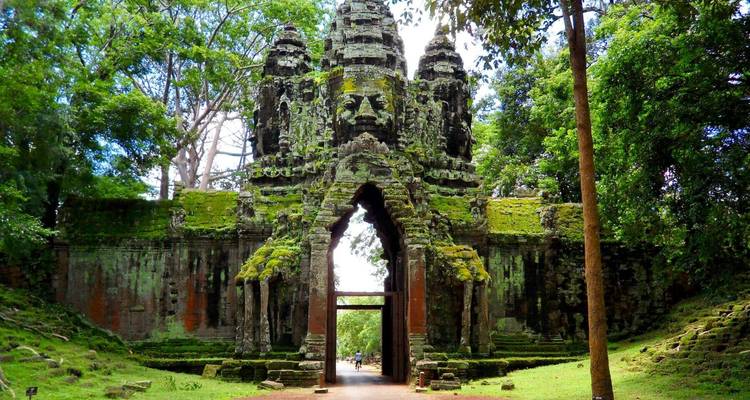 Ancient stone gate with intricate carvings surrounded by lush vegetation.